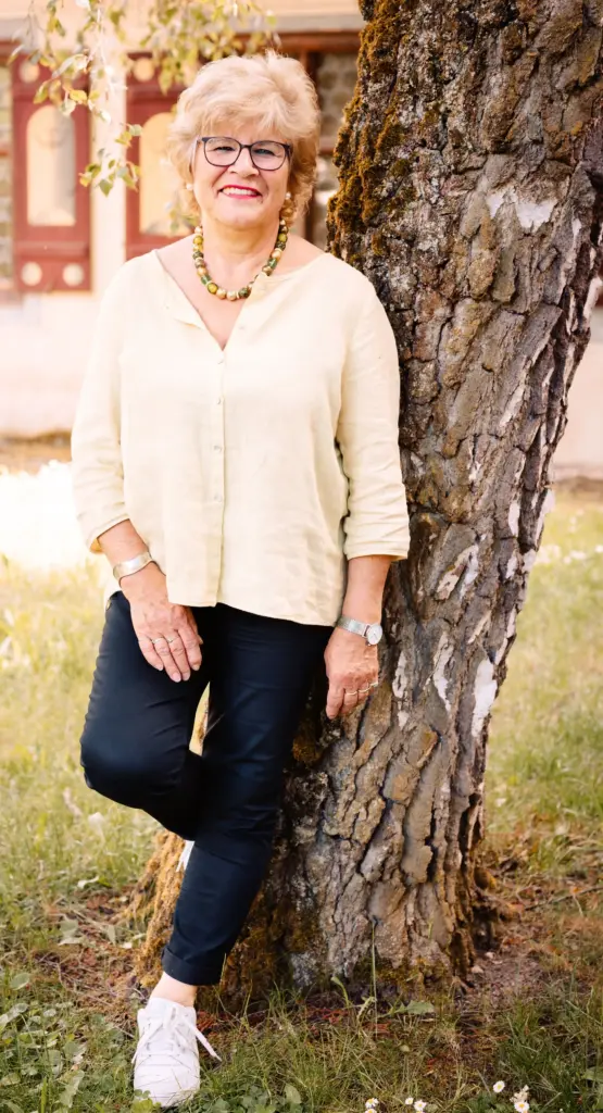 Gerda Hagen stehend an einem Baum angelehnt.